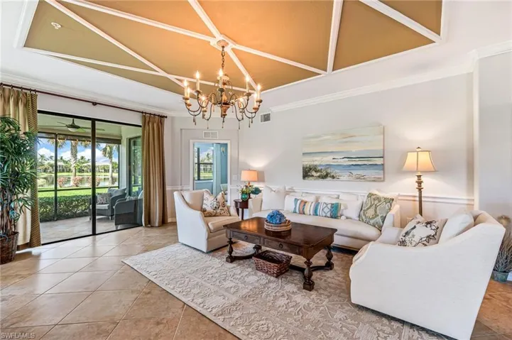 Tiled living room with an inviting chandelier, a towering ceiling, and ornamental molding