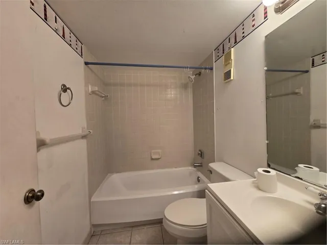 Full bathroom with tile floors, tiled shower / bath combo, toilet, and vanity with extensive cabinet space
