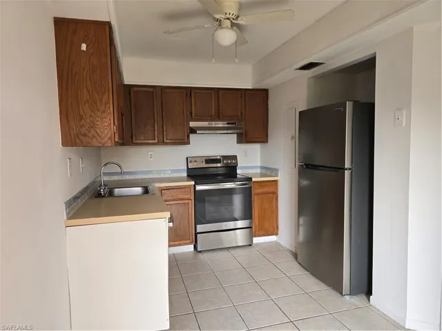 Kitchen featuring ceiling fan, refrigerator, fume extractor, sink, and electric stove