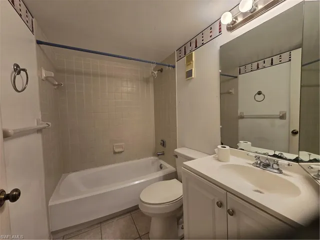 Full bathroom with tiled shower / bath, tile flooring, toilet, and vanity