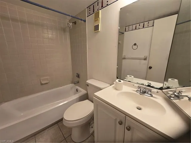 Full bathroom featuring tile floors, toilet, oversized vanity, and tiled shower / bath