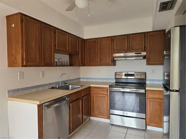 Kitchen featuring range hood, stove, sink, refrigerator, and dishwasher