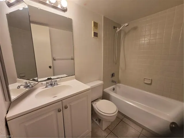 Full bathroom featuring tile floors, toilet, tiled shower / bath combo, and vanity