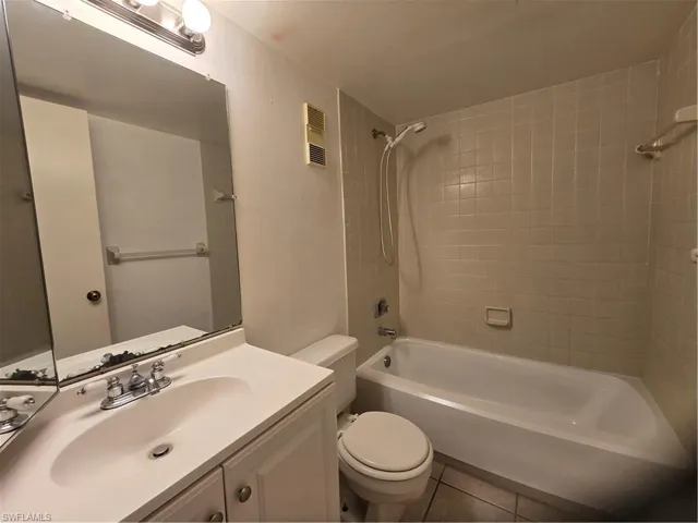 Full bathroom featuring tile floors, toilet, oversized vanity, and tiled shower / bath
