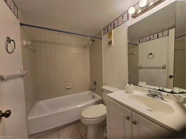 Full bathroom with tile flooring, tiled shower / bath combo, vanity, and toilet