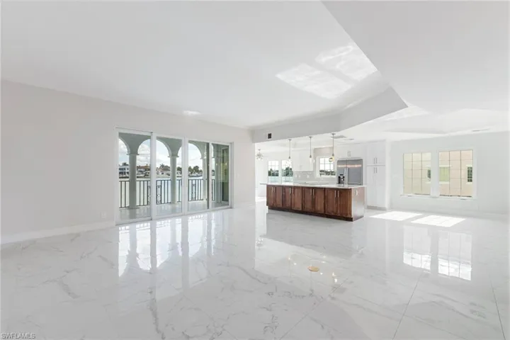 Unfurnished living room with plenty of natural light, light marble finish flooring, and crown molding