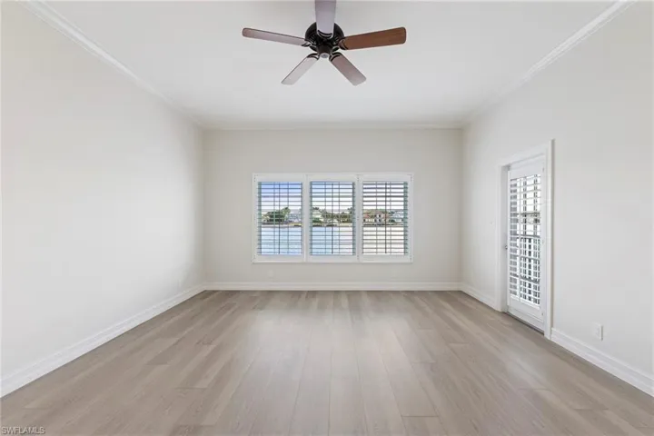 Empty room with ornamental molding, light wood-style flooring, and a ceiling fan