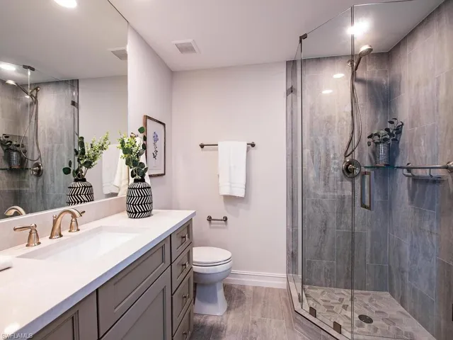 Bathroom with toilet, a shower with door, and vanity