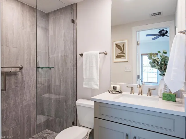 Bathroom with tiled shower, vanity, and toilet