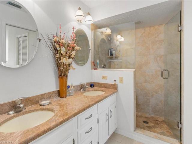 En-suite primary bath with newer walk-in shower, vanity with double sinks, decor lighting and mirrors.