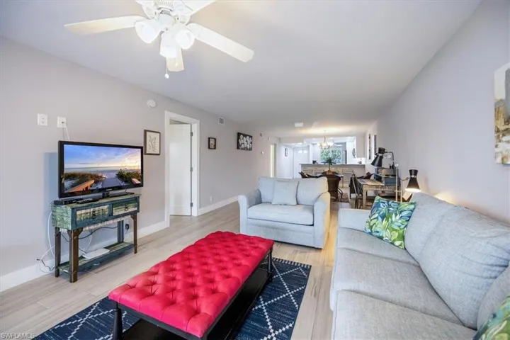 Living room featuring ceiling fan with notable chandelier and hardwood / wood-style flooring