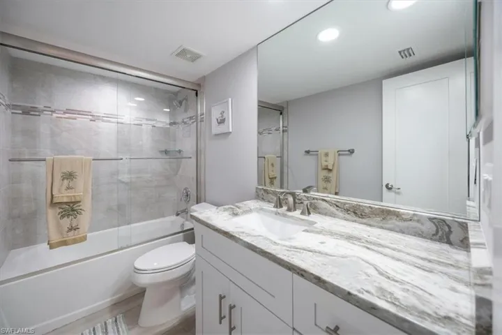 Full bathroom featuring combined bath / shower with glass door, vanity, and toilet