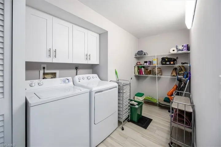 Laundry area featuring light wood-type flooring, cabinets, and washing machine and clothes dryer