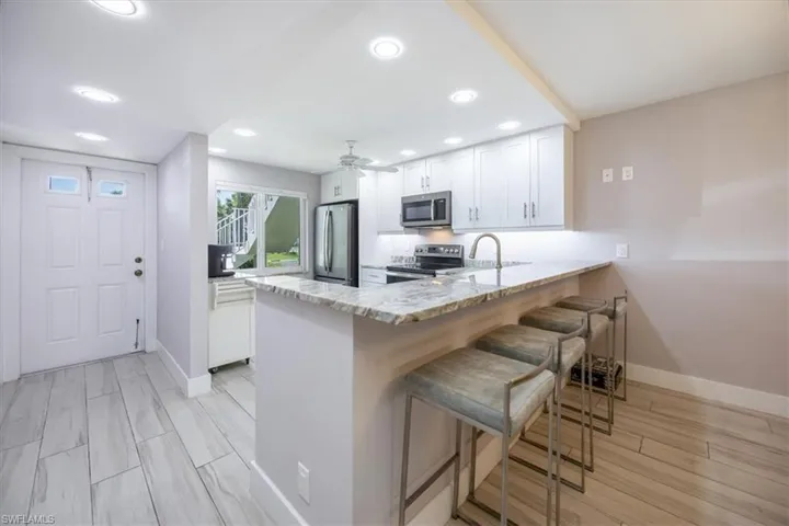 Kitchen featuring light wood-type flooring, appliances with stainless steel finishes, white cabinetry, and kitchen peninsula