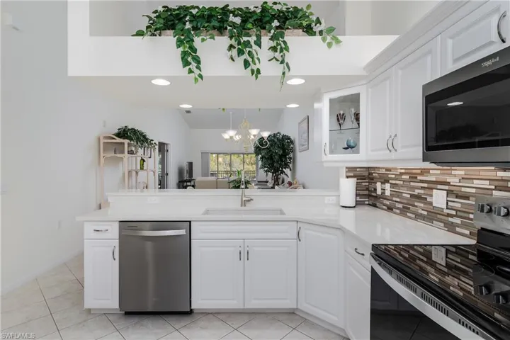 Modern kitchen featuring white cabinetry, light-toned countertops, and a mosaic tile backsplash
