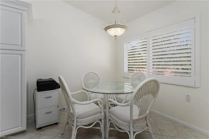 Dining area featuring plantation shutters, overhead chandelier lighting, and a built-in storage cabinet