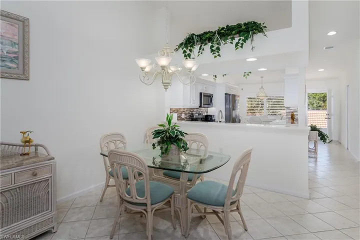 Dining area with a five-light chandelier, vaulted ceilings, and tile flooring