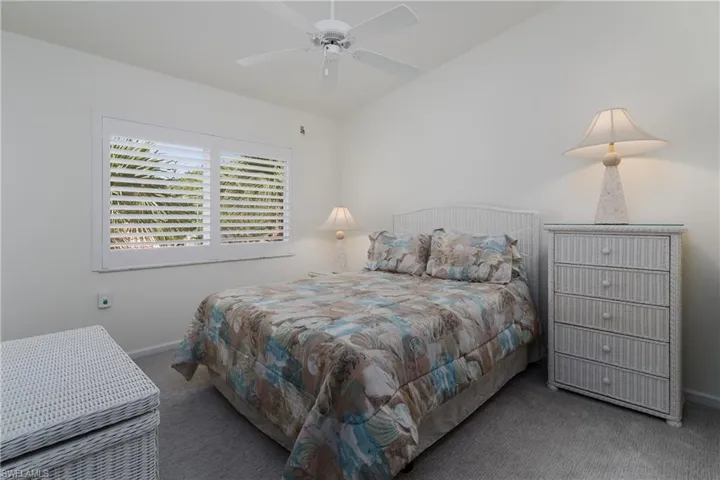 Bright interior room featuring a window with white plantation shutters, a ceiling fan, and light-colored wall-to-wall carpeting