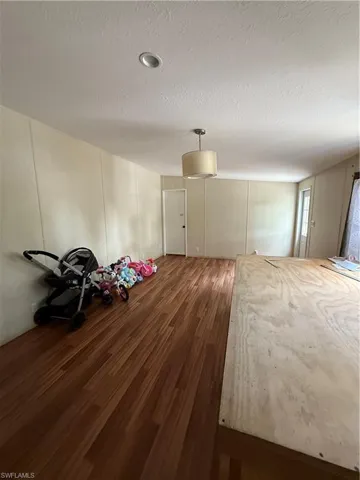 Unfurnished bedroom with dark wood-type flooring, a textured ceiling, and a decorative wall