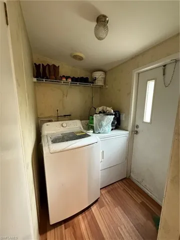 Laundry area featuring light wood-style floors, separate washer and dryer, and wallpapered walls
