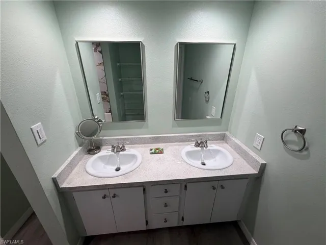 Double vanity with white cabinetry, light speckled countertop, dual undermount sinks, and individual framed mirrors