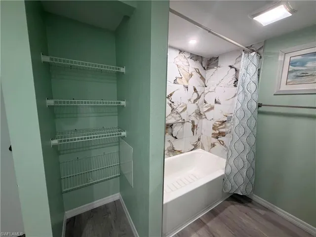 Bathroom featuring a tub/shower combination with large format marble-look tile surround and a recessed niche