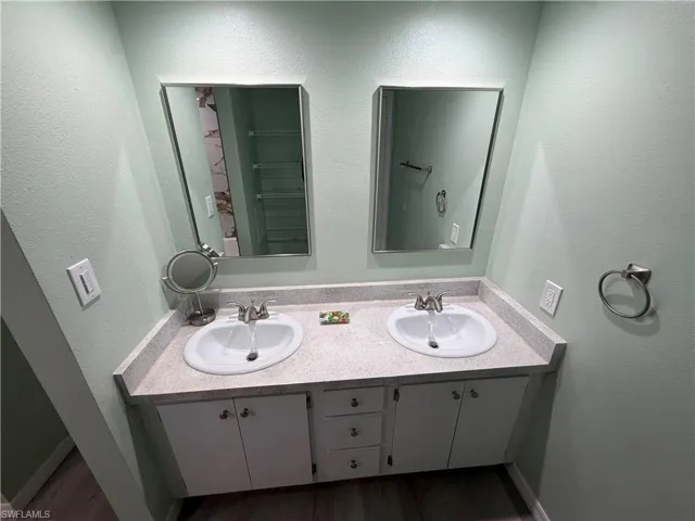 Double vanity with white cabinetry, light speckled countertop, and two framed mirrors