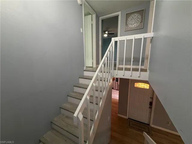 Staircase featuring wood-finish flooring treads and risers with white painted railings