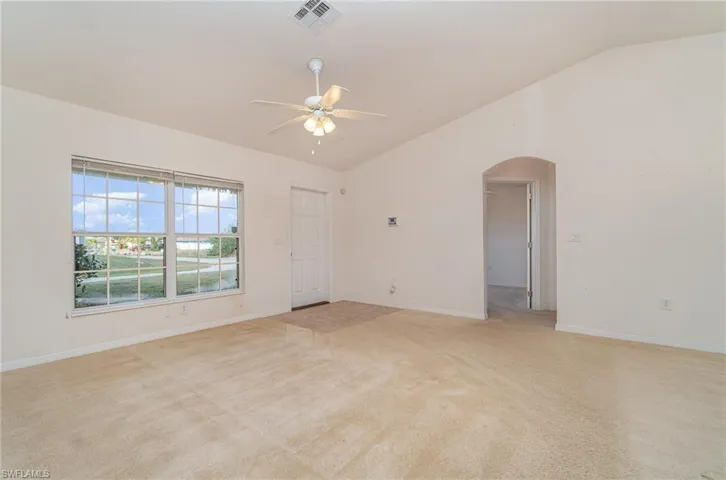 Carpeted spare room with ceiling fan and lofted ceiling