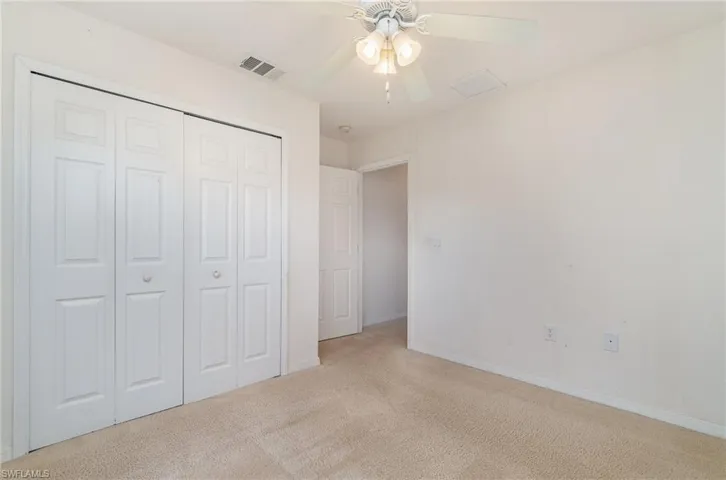 Unfurnished bedroom with a closet, ceiling fan, and light colored carpet