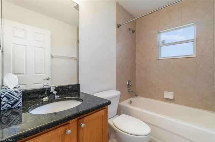 Full bathroom with tiled shower / bath, vanity, and toilet