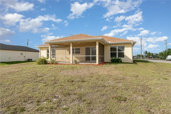 Rear view of house with a sunroom, a yard, and cooling unit