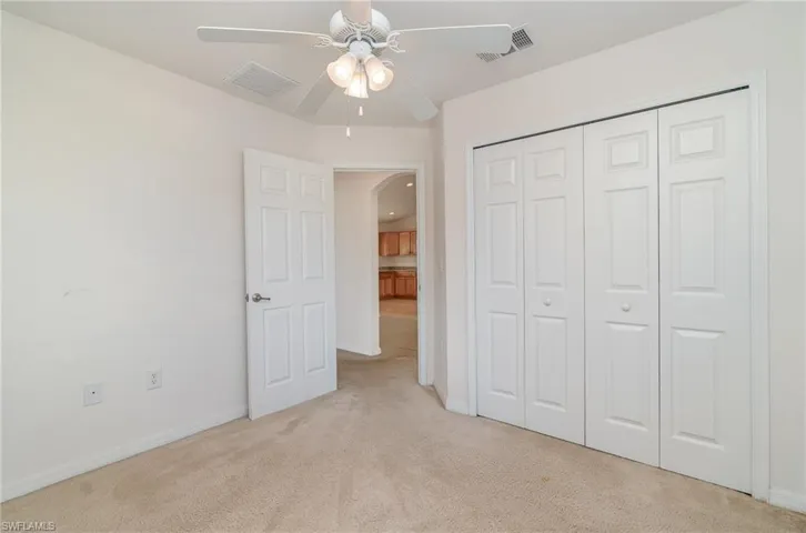 Unfurnished bedroom featuring ceiling fan, light colored carpet, and a closet