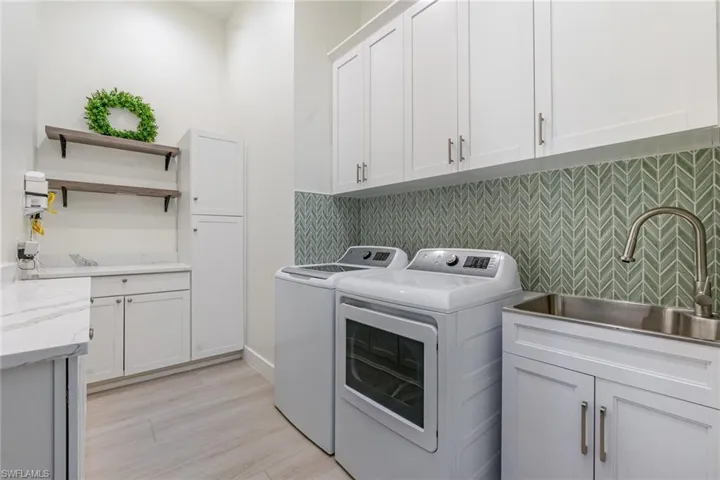 Laundry area featuring cabinet space, separate washer and dryer, and light wood-type flooring and sink