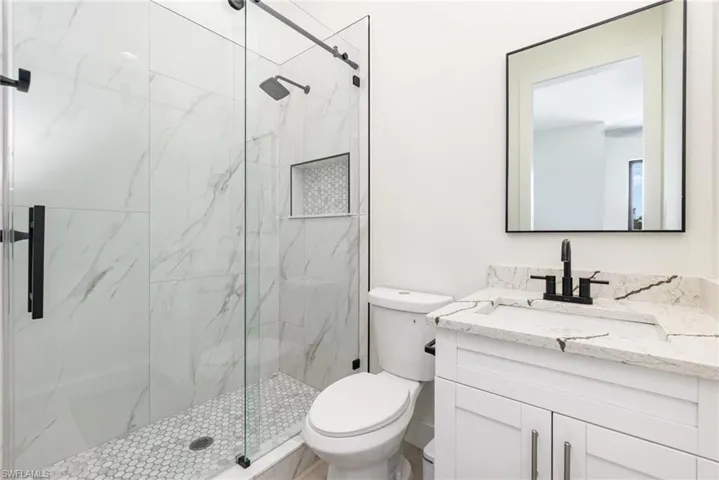 Bathroom featuring vanity and a marble finish shower