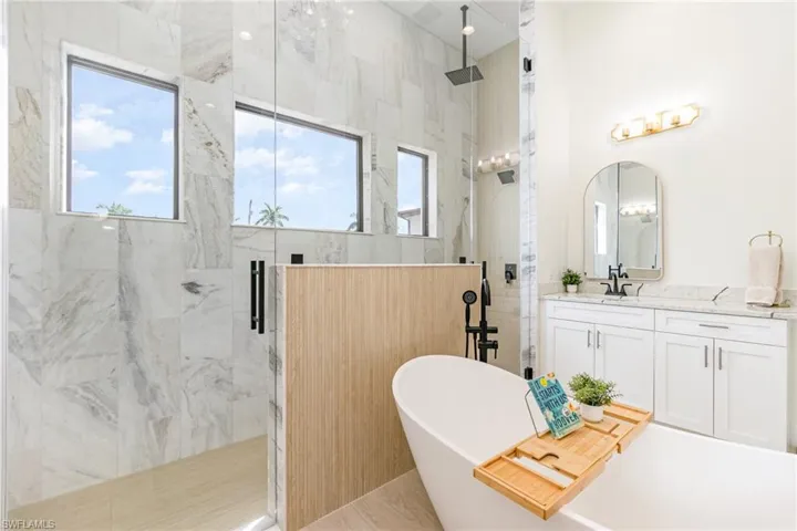 Full bathroom featuring vanity, a soaking tub, and a marble finish shower