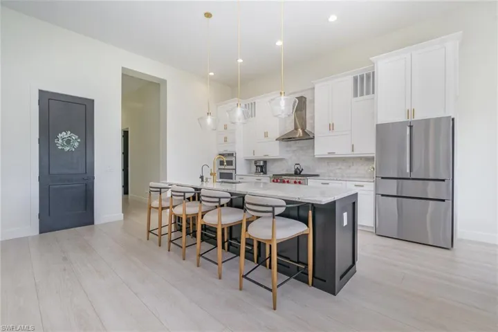 Kitchen featuring appliances with stainless steel finishes, white cabinets, light stone countertops, pendant lighting, and recessed lighting