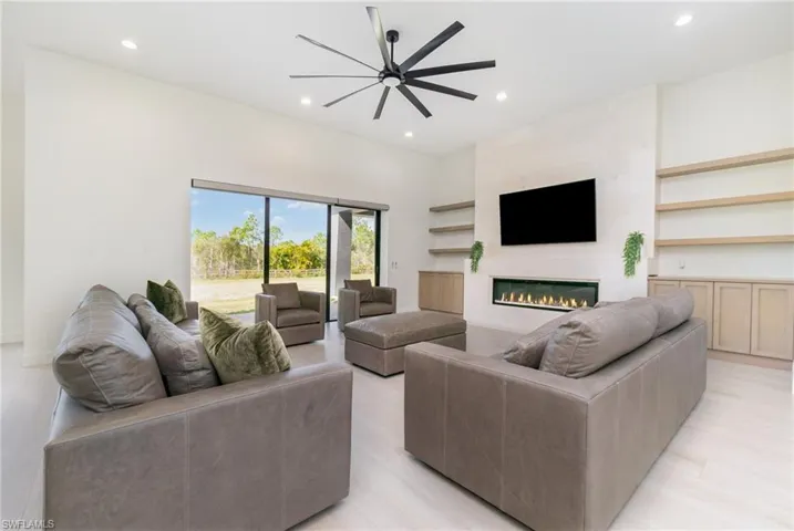 Living room featuring recessed lighting, a fireplace, a ceiling fan, and light wood-tile floors