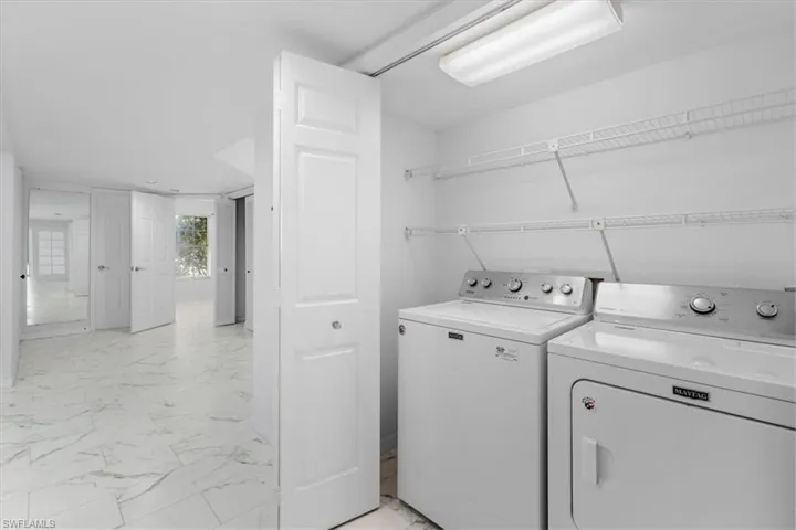 Clothes washing area with washer and clothes dryer and light tile patterned floors