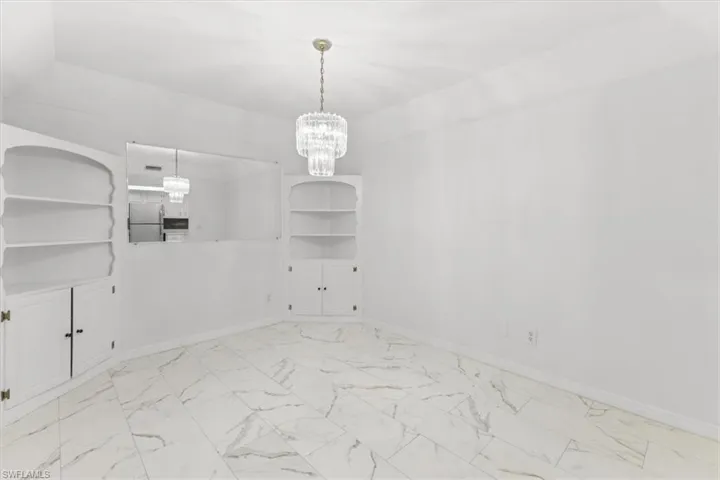 Unfurnished room with light tile patterned flooring and a chandelier