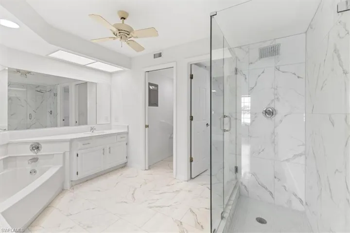Bathroom with tile patterned flooring, separate shower and tub, vanity, and ceiling fan