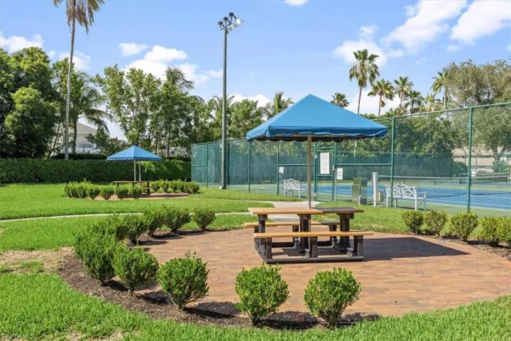 View of property's community featuring tennis court and a yard