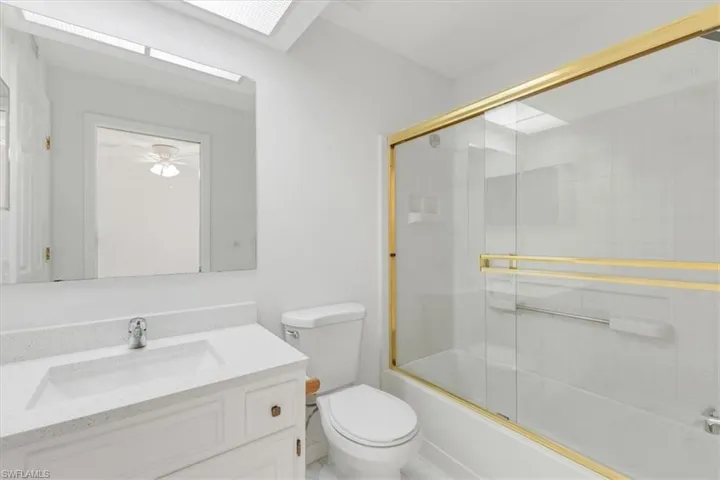 Full bathroom with vanity, combined bath / shower with glass door, tile patterned flooring, and toilet