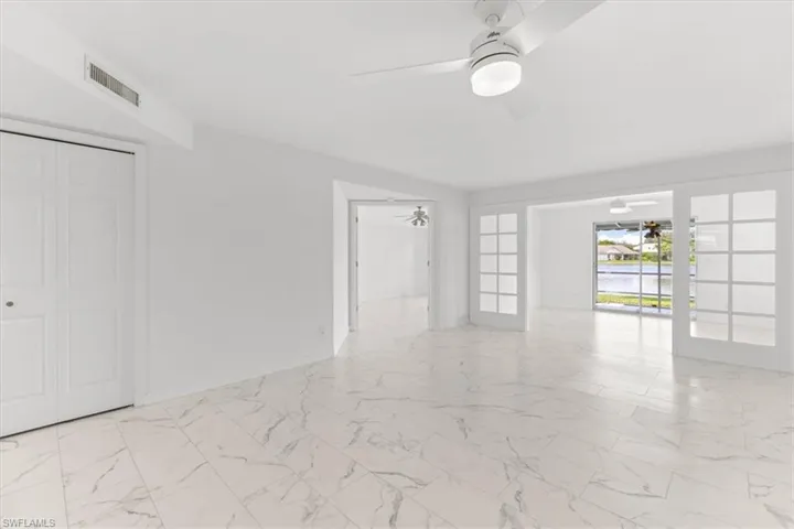 Tiled spare room featuring french doors and ceiling fan