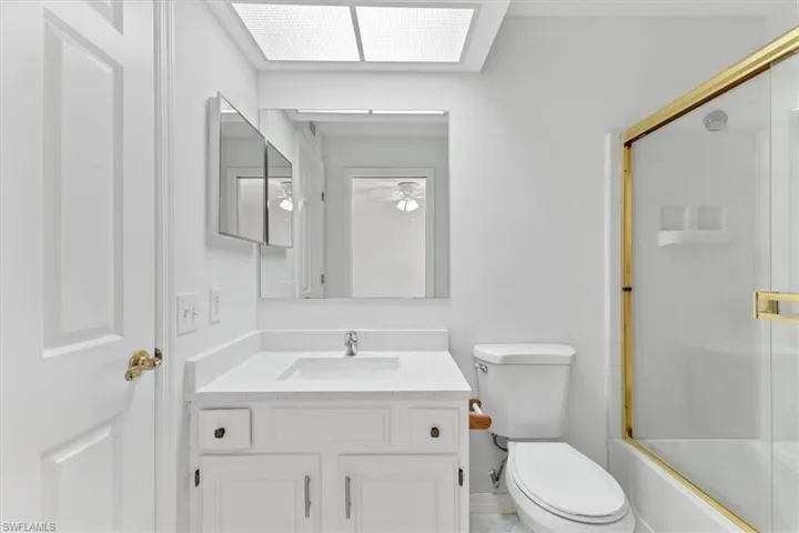 Full bathroom featuring vanity, toilet, tile patterned flooring, and bath / shower combo with glass door
