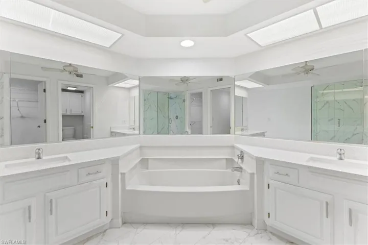 Bathroom featuring vanity, ceiling fan, a bath, and tile patterned flooring