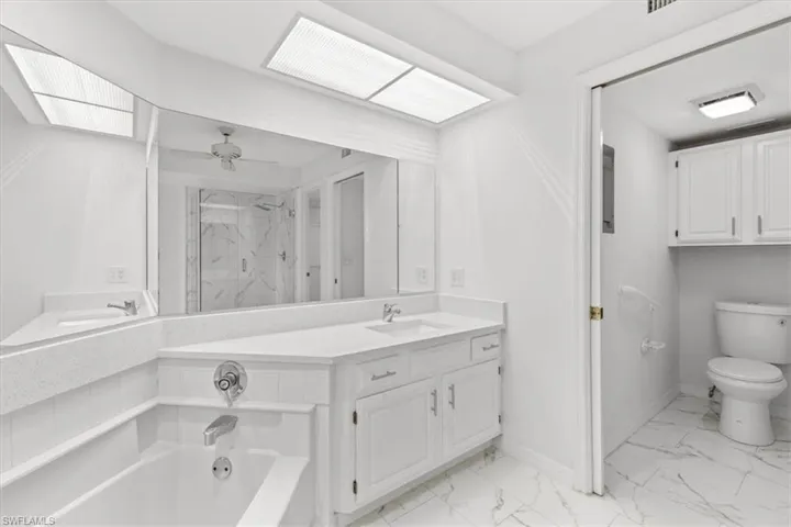 Bathroom featuring vanity, tile patterned floors, ceiling fan, a bathtub, and toilet