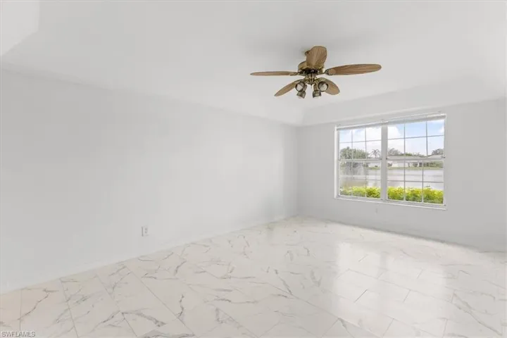 Tiled empty room featuring a water view and ceiling fan
