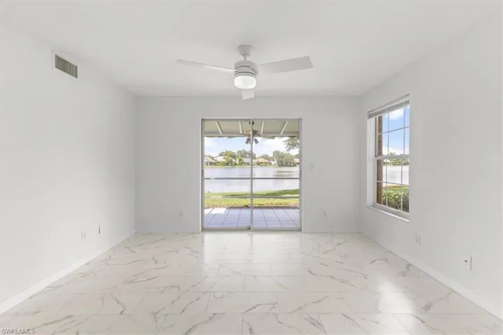 Tiled spare room featuring a water view and ceiling fan