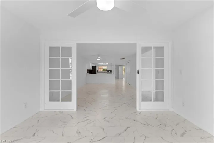 Tiled empty room featuring ceiling fan and french doors